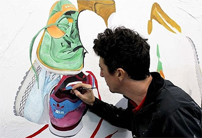 Lalo Cruces pintando zapatillas mural